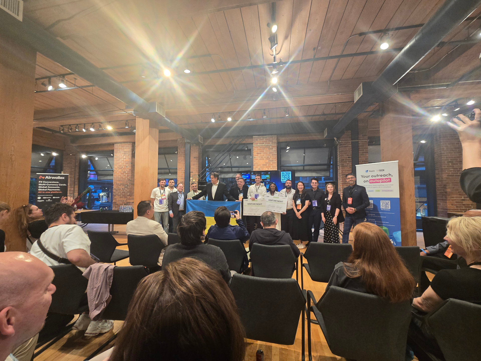 UATECH Venture Night winners on stage with oversized cheques and the Ukrainian flag at the Websummit Vancouver side event