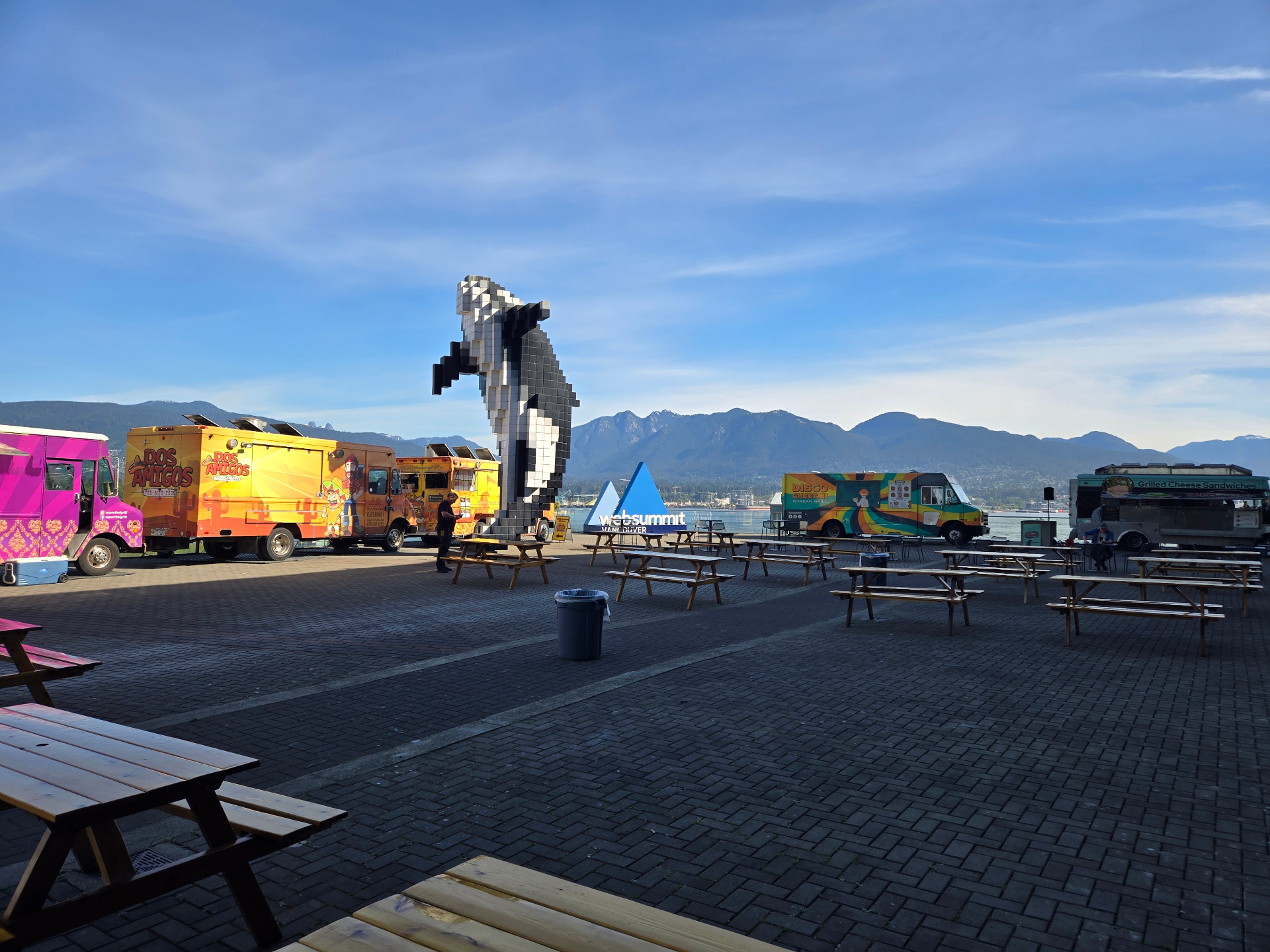 Websummit Vancouver outdoor food-truck plaza with the pixelated orca sculpture and the North Shore mountains